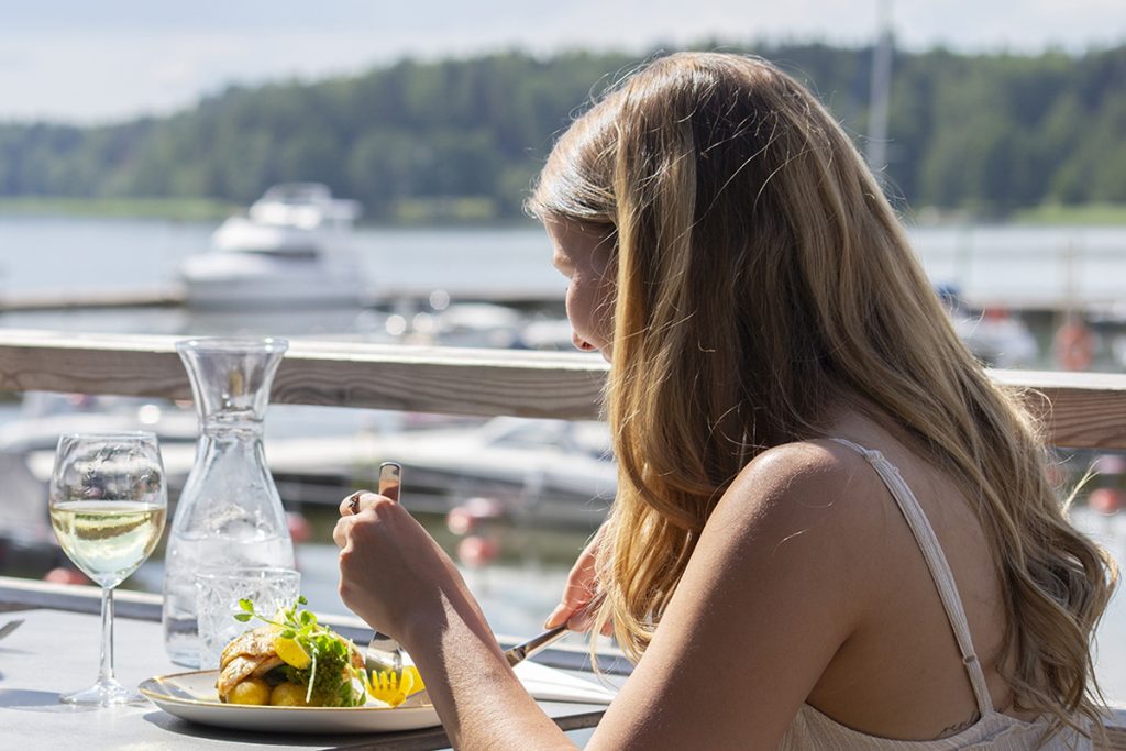 Ruokailija aurinkoisella terassilla, josta on merinäkymä.