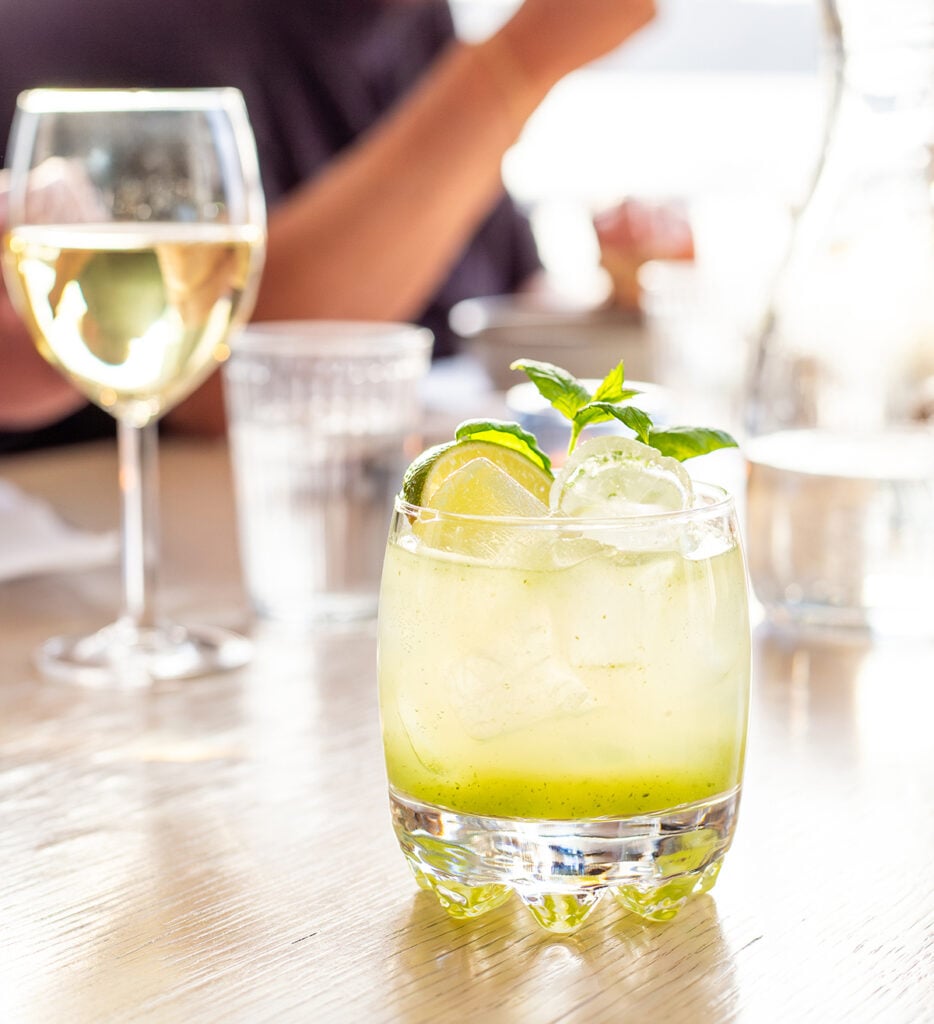 Ruokapöydälle aseteltu hennon limenvihreä cocktail matalassa lasissa.