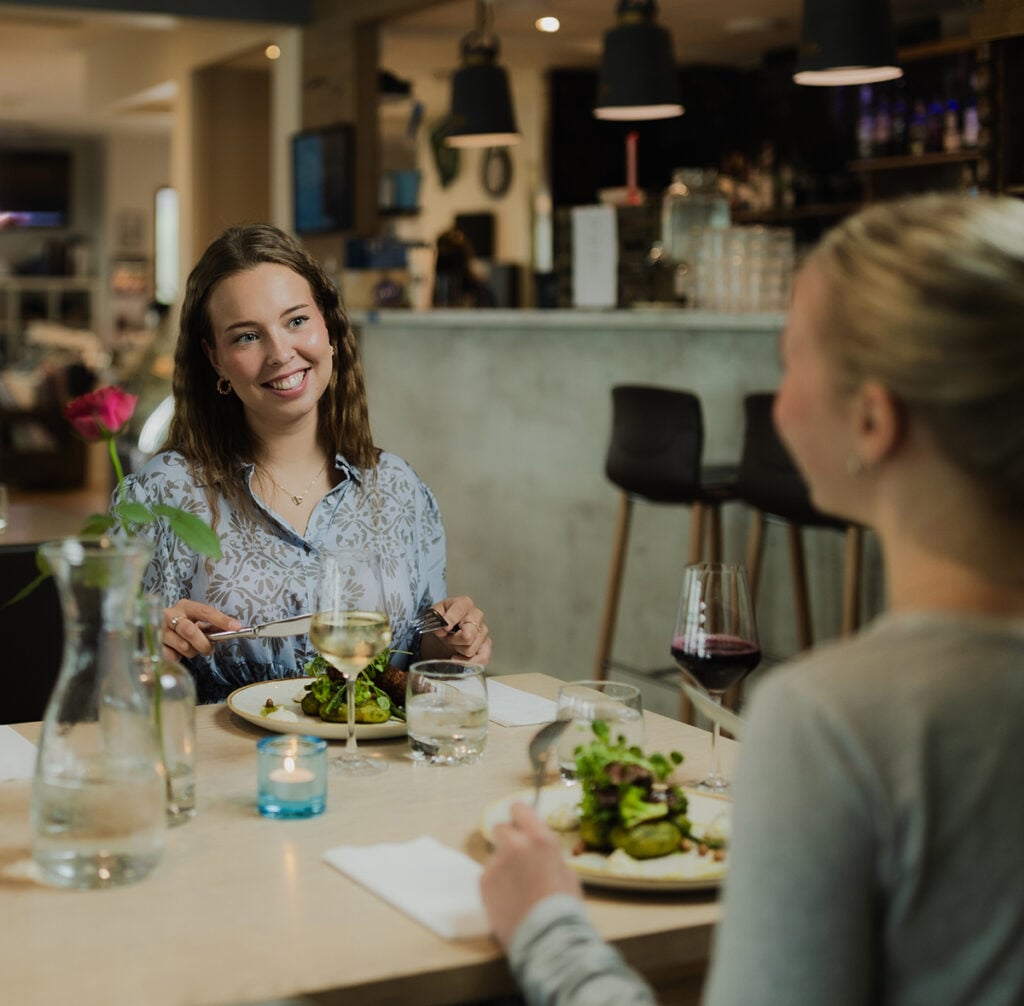 Naiset syömässä ruokaa ravintolassa, baaritiski taustalla