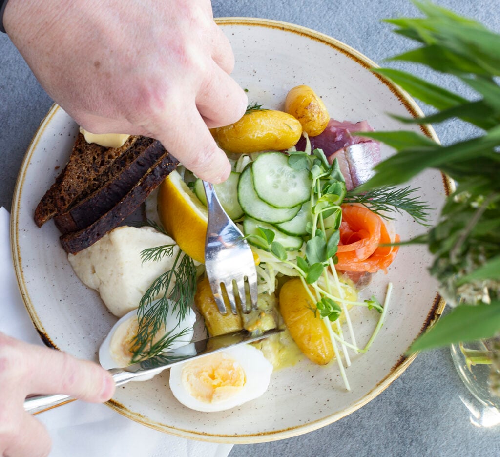 Lautasella kokoelma ruokaa, ruokailija iskenyt haarukan ja veitsen jo ruokaan
